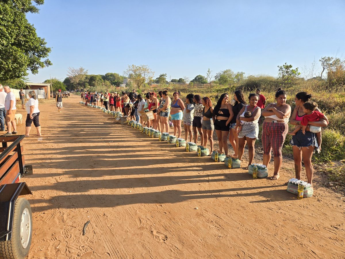 Villagers lining up to receive pre-packed boxes of food and supplies in a Brazilian favela